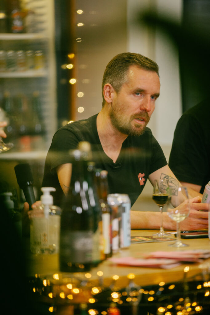 Mikkel Borg Bjergsø sidder i samtale ved ølsmagning på sin bar. Omkring ham ses julelyskæder.